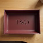 Amenities hotel personalizados: bandeja de cuero grabada sobre mesa de roble
