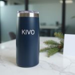 Regalos de navidad para empleados: termo de acero inoxidable azul marino sobre mármol blanco con rama de pino