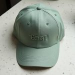riesgos de vender merchandising: gorra de algodón verde salvia sobre mesa de terrazo en una oficina